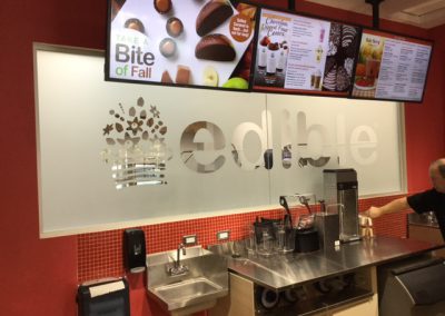 Frost window film with retail store logo cut out on glass between kitchen and counter