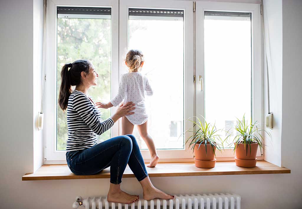 Women and child in front of bright windows in their home