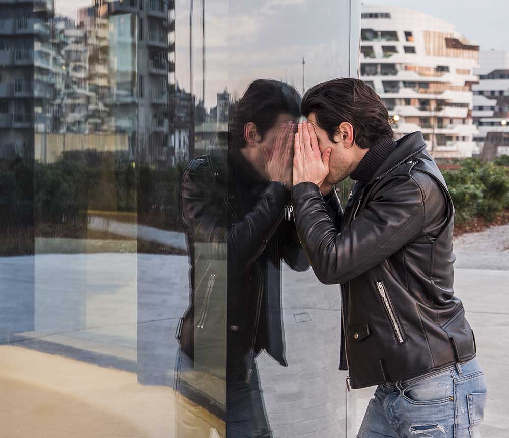 Man holding face to glass to look through windows
